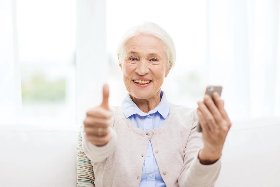 Senior woman holding a phone and a thumbs up